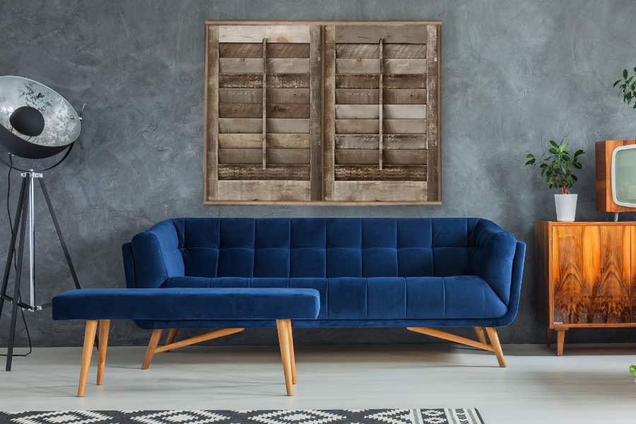 A blue couch against a gray wall with reclaimed wood interior shutters