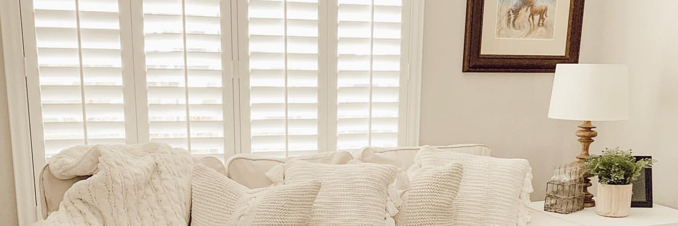 Photo Credit: @farmgirlandherpup White and beige living room with white polywood shutters above a white couch.