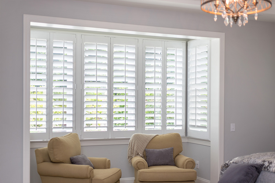 White Polywood shutters in a sitting area of a bedroom.