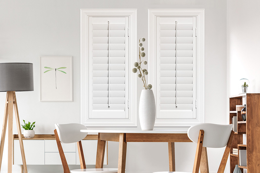 Sunburst's selection of stylish window treatments for designers in Miami makes it easy to find the perfect ones for every design job.  White Polywood shutters on two windows in a modern Scandinavian-style room