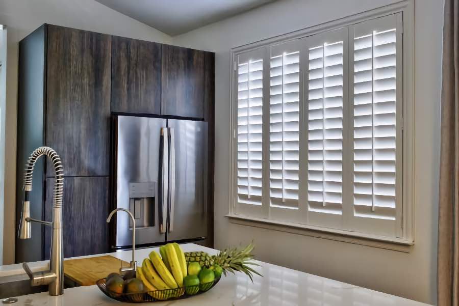 Homeowners use indoor window shutters in Miami when they want attractive and functional window treatments. Polywood shutters on a large kitchen window